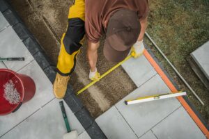 Paver patio contractor measuring the size of concrete blocks