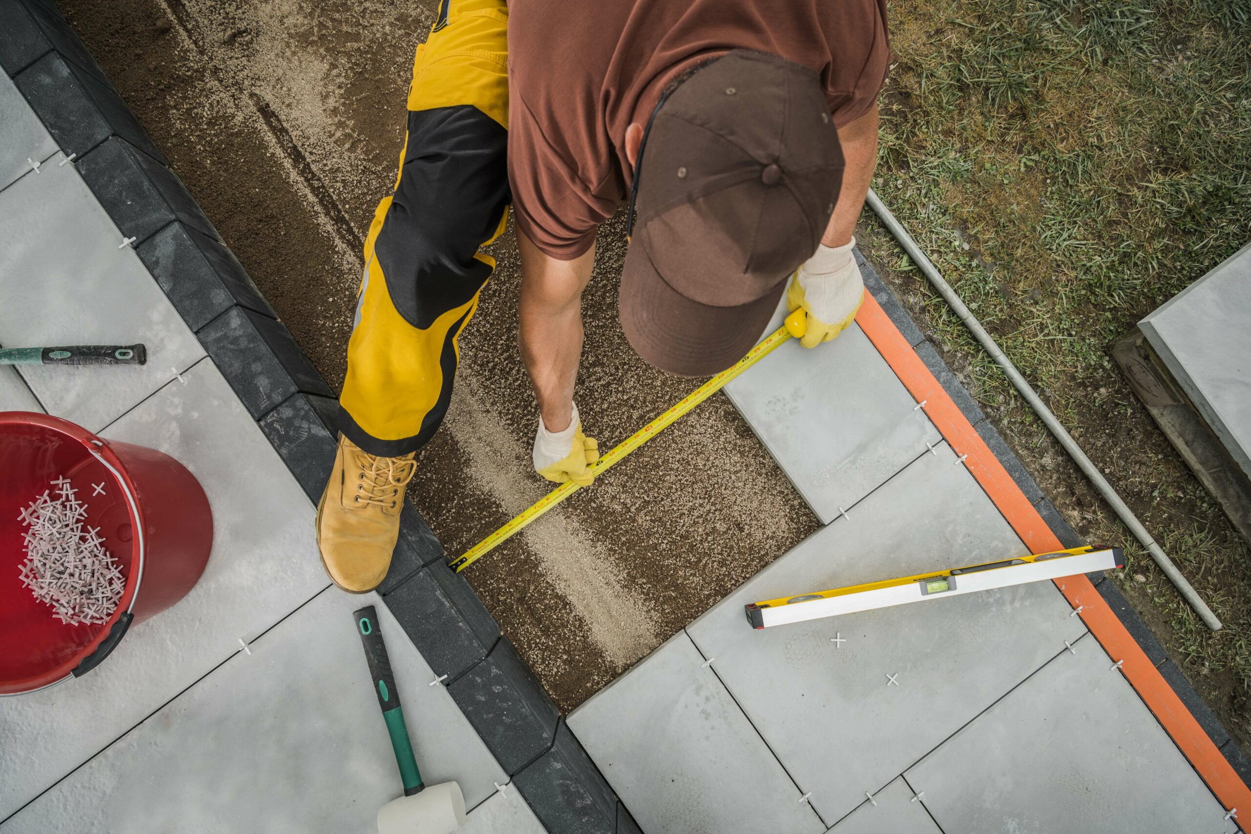 Paver patio contractor measuring the size of concrete blocks